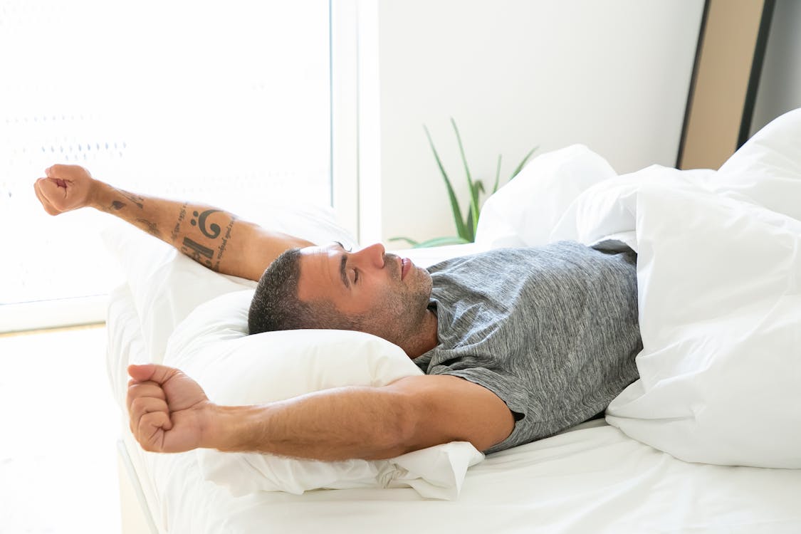 Man waking up and stretching in bed in the morning